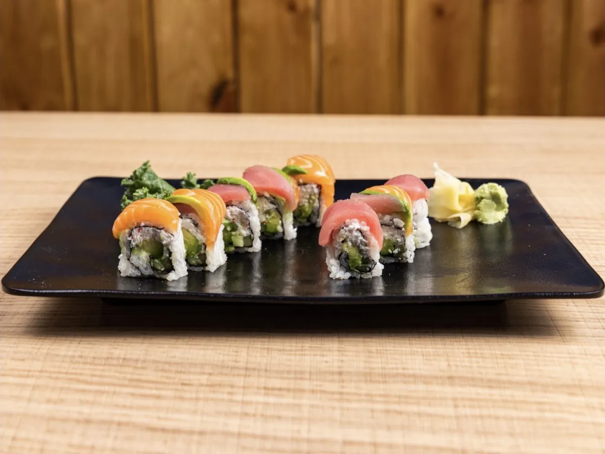 Rainbow Roll topped with alternating slices of tuna, salmon and avocado, plated with ginger and wasabi